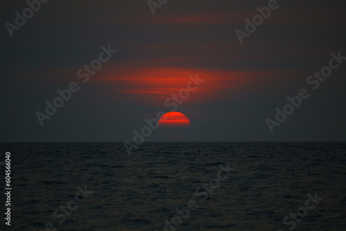 sunset on the sea, dark sunset, red-orange semi-circle sun