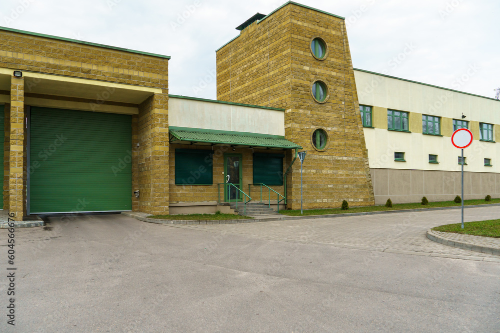 A large modern garage made of beige brick and green roller gates. Video surveillance system at the entrance to the garage. Safe conditions for storing cars and property. A large modern garage made of beige brick and green roller gates. Video surveillance system at the entrance to the garage. Safe conditions for storing cars and property.