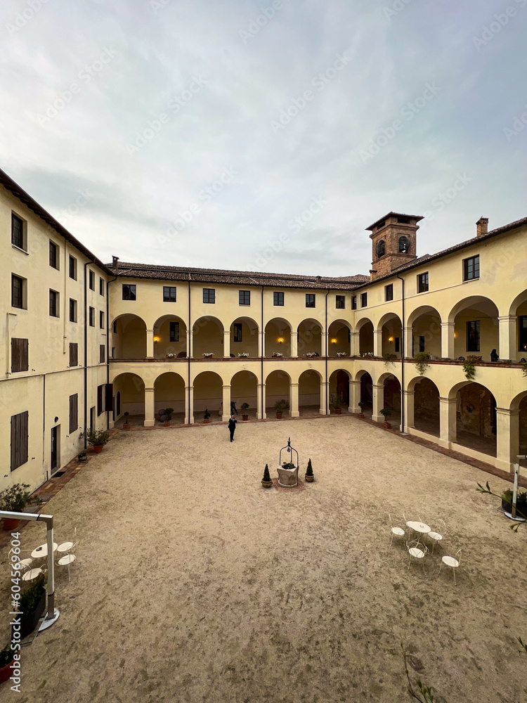 inner courtyard of ancient monastery with tables. Parma area, Italy