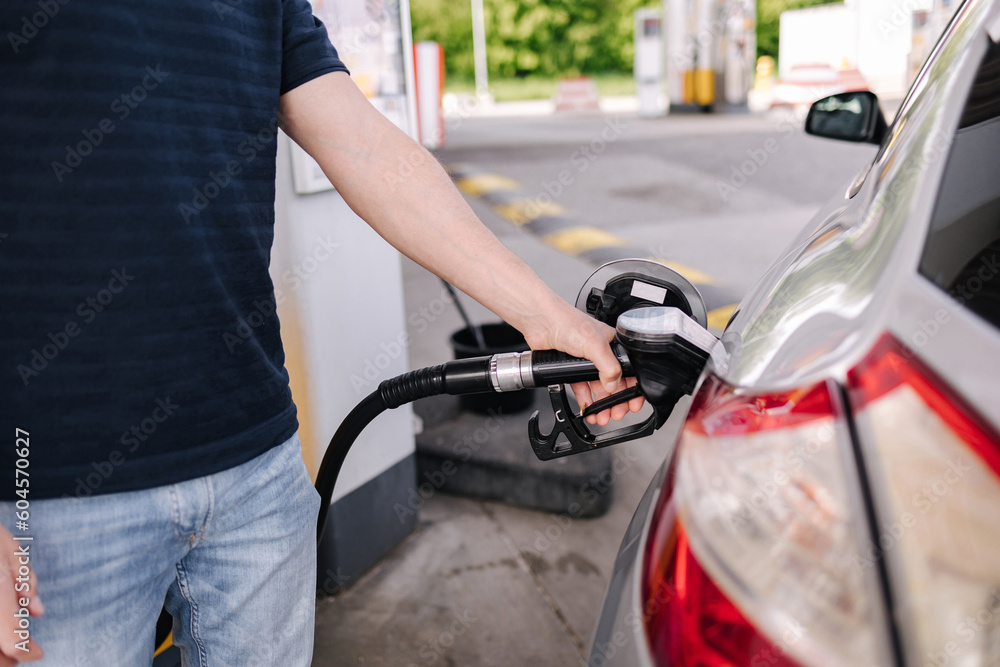 Man refueling the car at a gas station. Close-up of driver hand pumping gasoline car with fuel at the refuel station. Man refueling the car at a gas station. Close-up of driver hand pumping gasoline car with fuel at the refuel station.