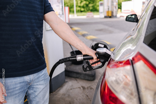 Man refueling the car at a gas station. Close-up of driver hand pumping gasoline car with fuel at the refuel station.