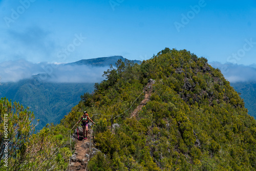 Young female backpacker hiking by the mountain above the cloud route at the end of april on Madeira island, Portugal. Active people around World traveling concept.