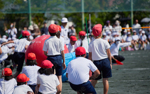 小学校の運動会で空飛ぶ大玉のゲームを遊んでいる学生達