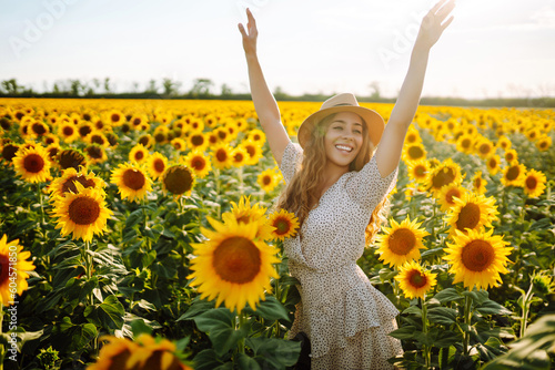 Happy young woman surrounded by yellow sunflowers in full bloom, in a flower garden, traveling on holiday.