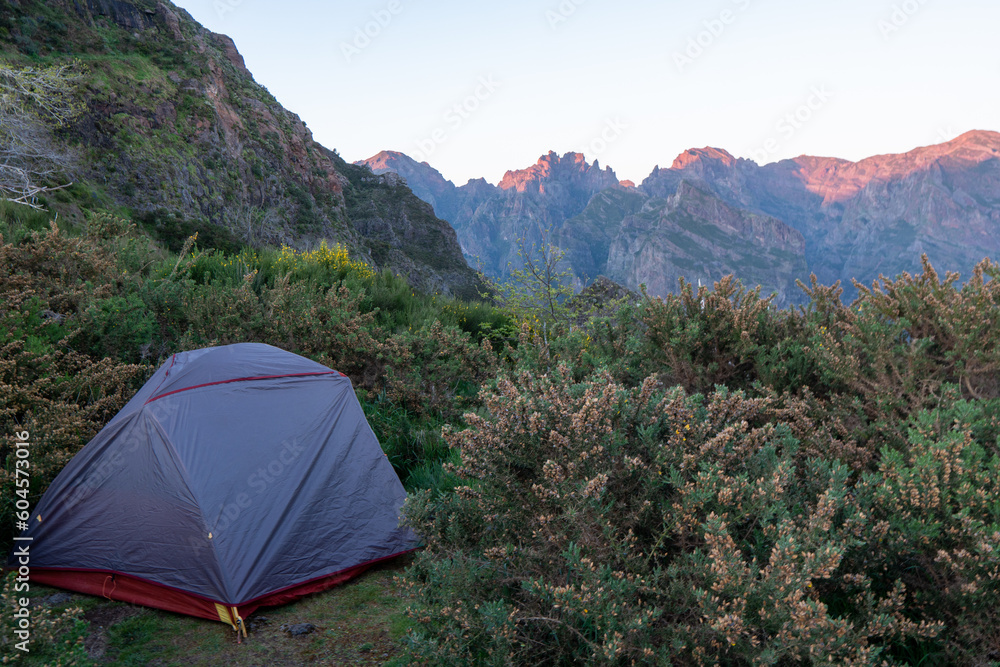 Gray camping tent on top of mountain with amazing sunrise on background. Time spending on fresh air. Travelling concept.