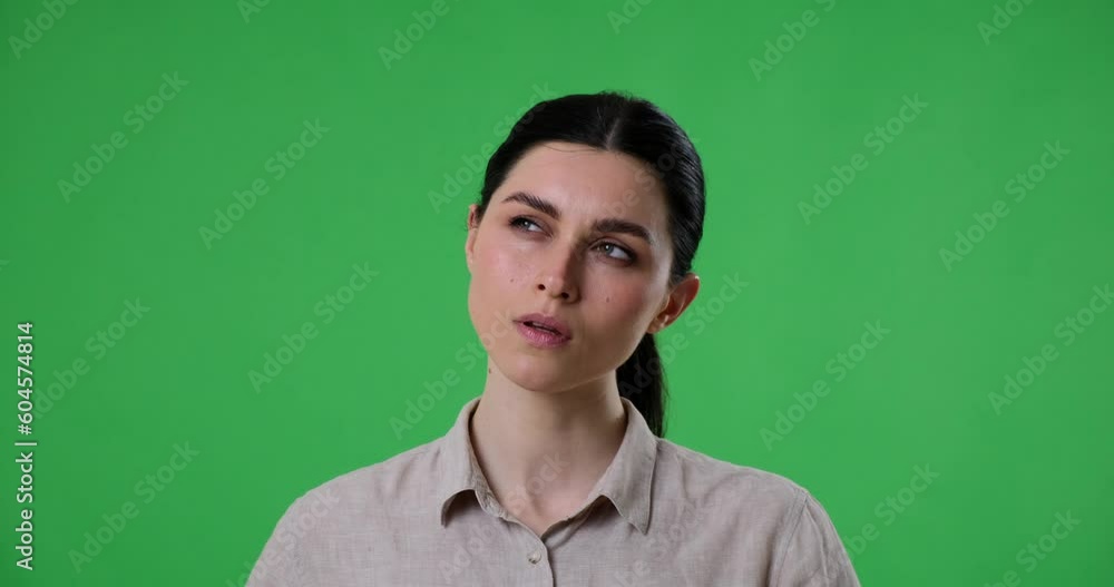 Caucasian woman is standing on a green screen background, thinking and searching for an idea. She looks around until an idea finally comes to her, and she points finger up, indicating genius solution. Caucasian woman is standing on a green screen background, thinking and searching for an idea. She looks around until an idea finally comes to her, and she points finger up, indicating genius solution.