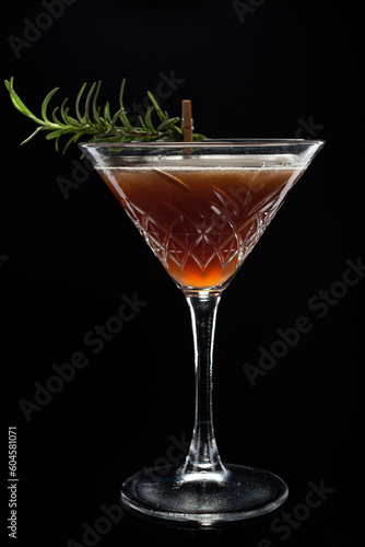 Alcoholic cocktail Cosmopolitan cocktail decorated with rosemary on martini glass on black background. Copy Space. 