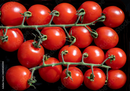 View from above of group red fresh ripened cherry tomatoes on black background.