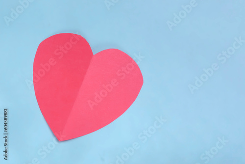 Red paper heart on blue background with copy space. Valentines day concept.