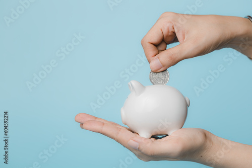 Hand saving a coin into pig...