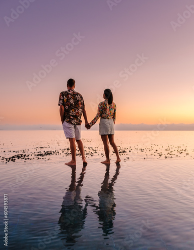 couple man and women in front of Infinity pool looking out over the ocean of Cape Town South Africa, man and woman in a swimming pool during sunset.  photo