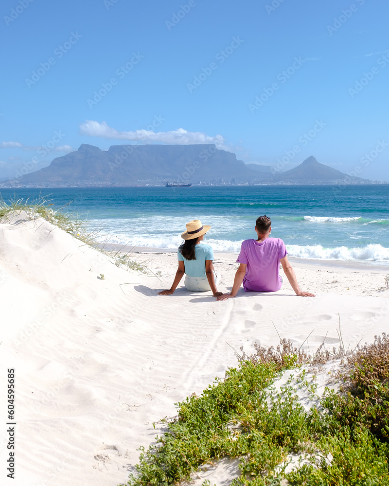 Fototapeta premium Bloubergstrand Cape Town South Africa on a bright summer day, couple on the beach, men and women chilling on the beach during vacation in Cape Town South Africa