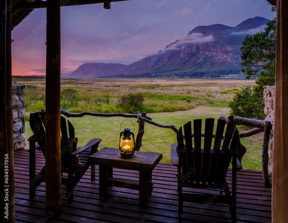 Fototapeta premium Mountains and grassland near Hermanus at the Garden Route Western Cape South Africa Whale coast. A lodge wooden bungalow with chairs during a vacation in South Africa at Susnet