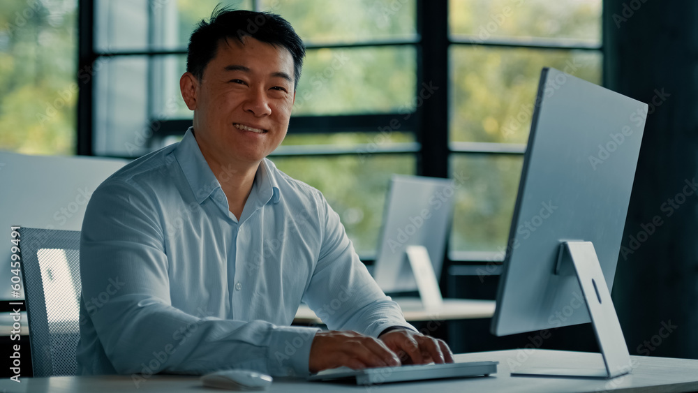 Mature Asian businessman chinese korean office worker specialist male work on computer develop project online look at camera confident smile. Portrait successful senior man business profession concept Mature Asian businessman chinese korean office worker specialist male work on computer develop project online look at camera confident smile. Portrait successful senior man business profession concept