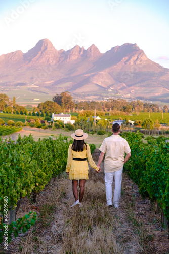 A couple of men and women are on vacation in South Africa at a Vineyard landscape with mountains in Stellenbosch, near Cape Town, South Africa photo