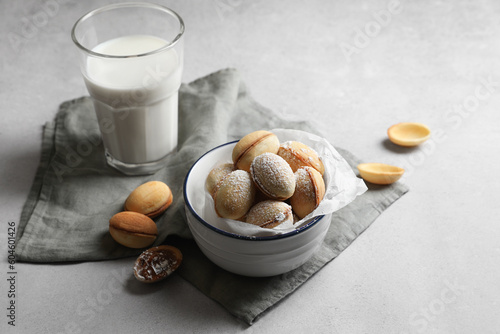 Delicious walnut shaped cookies with filling and milk on grey table