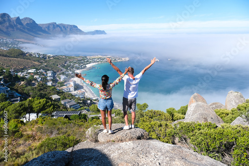 Wallpaper Mural a couple of men and women with hands up exiting at The Rock viewpoint in Cape Town over Campsbay, view over Camps Bay with fog over the ocean. fog coming in from the ocean Cape Town South Africa Torontodigital.ca