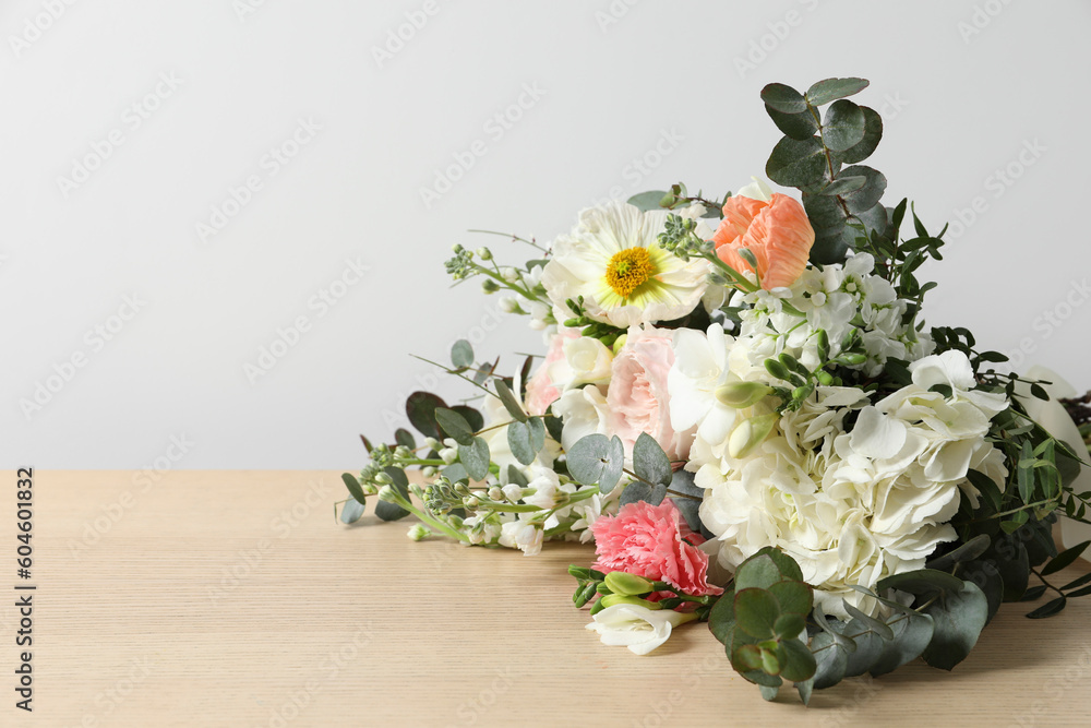 Bouquet of beautiful flowers on wooden table against white wall. Space for text - obrazy, fototapety, plakaty 