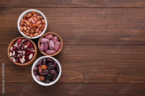 Different kinds of dry kidney beans on wooden table, flat lay. Space for text