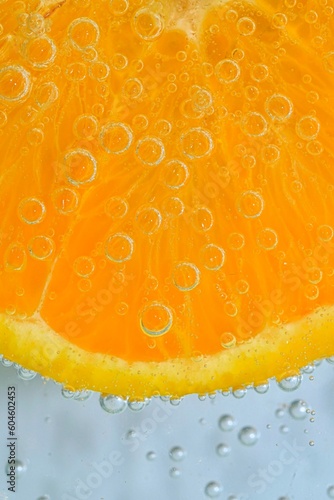 Slice of ripe orange fruit in water on white background. Close-up of orange fruit in liquid with bubbles. Slice of ripe orange fruit in sparkling water. Macro image of fruit in carbonated water.