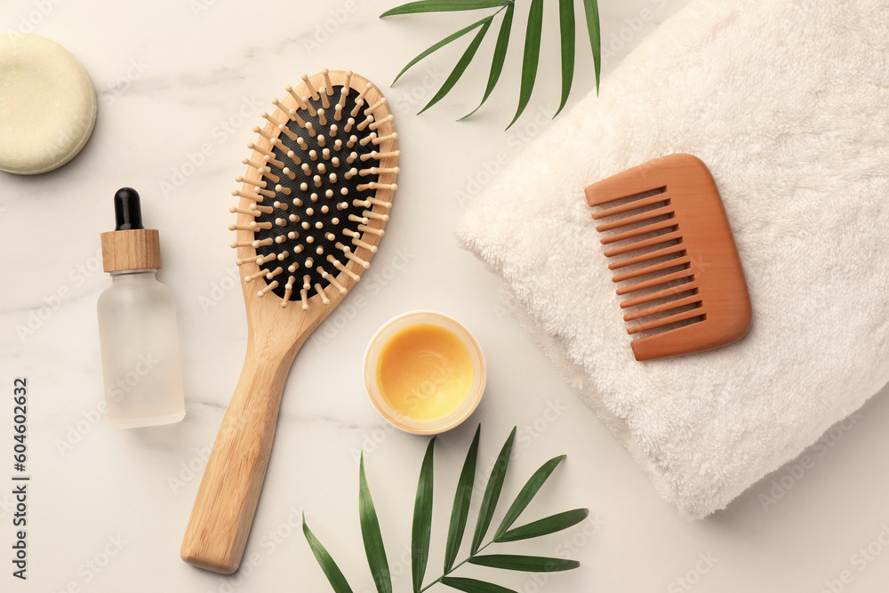 Flat lay composition with wooden hair brush and comb on white marble table - obrazy, fototapety, plakaty 