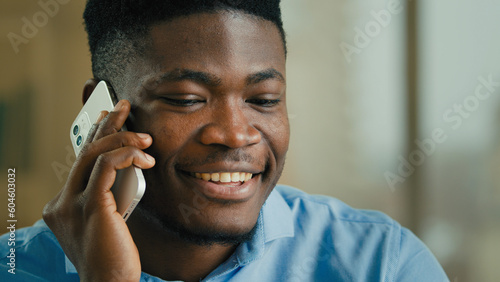 Close up african american man talking phone indoors ethnic smiling male 30s businessman speak with mobile smartphone call negotiate professional office worker entrepreneur manager communicating remote