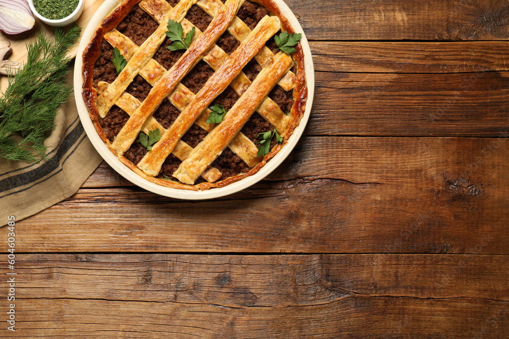 Freshly baked meat pie and products on wooden table, flat lay. Space for text