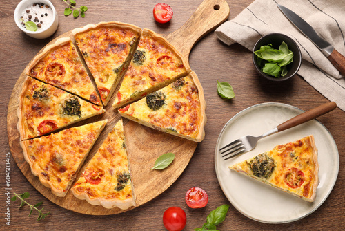 Delicious homemade vegetable quiche, ingredients and fork on wooden table, flat lay