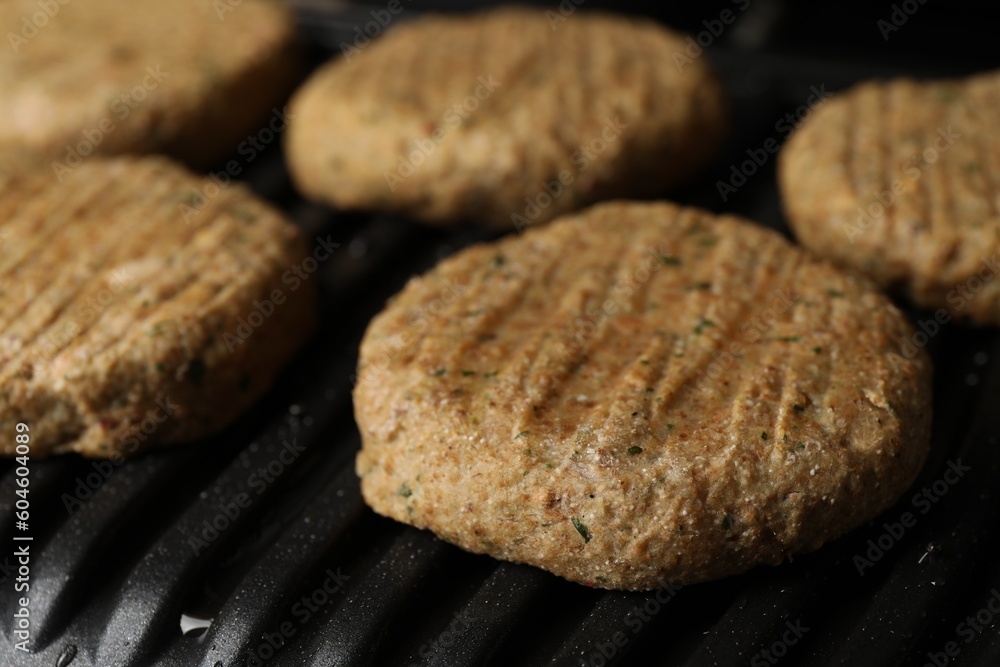 Delicious vegan cutlets cooking on electric grill, closeup Delicious vegan cutlets cooking on electric grill, closeup