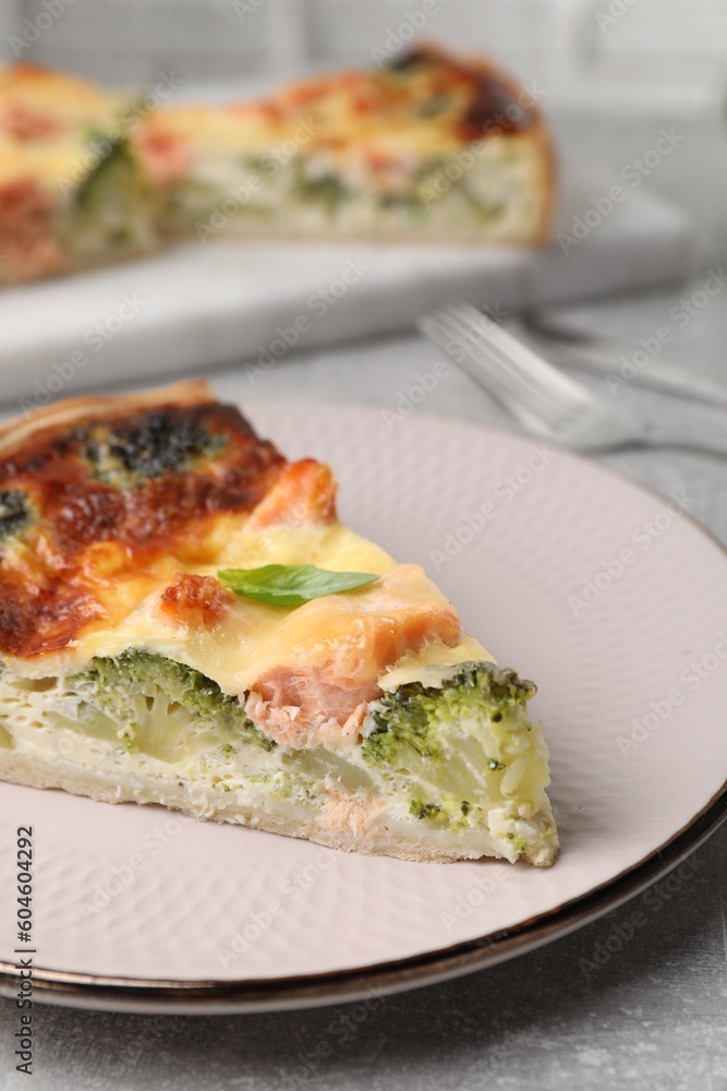 Piece of delicious homemade quiche with salmon and broccoli on light grey table, closeup Piece of delicious homemade quiche with salmon and broccoli on light grey table, closeup