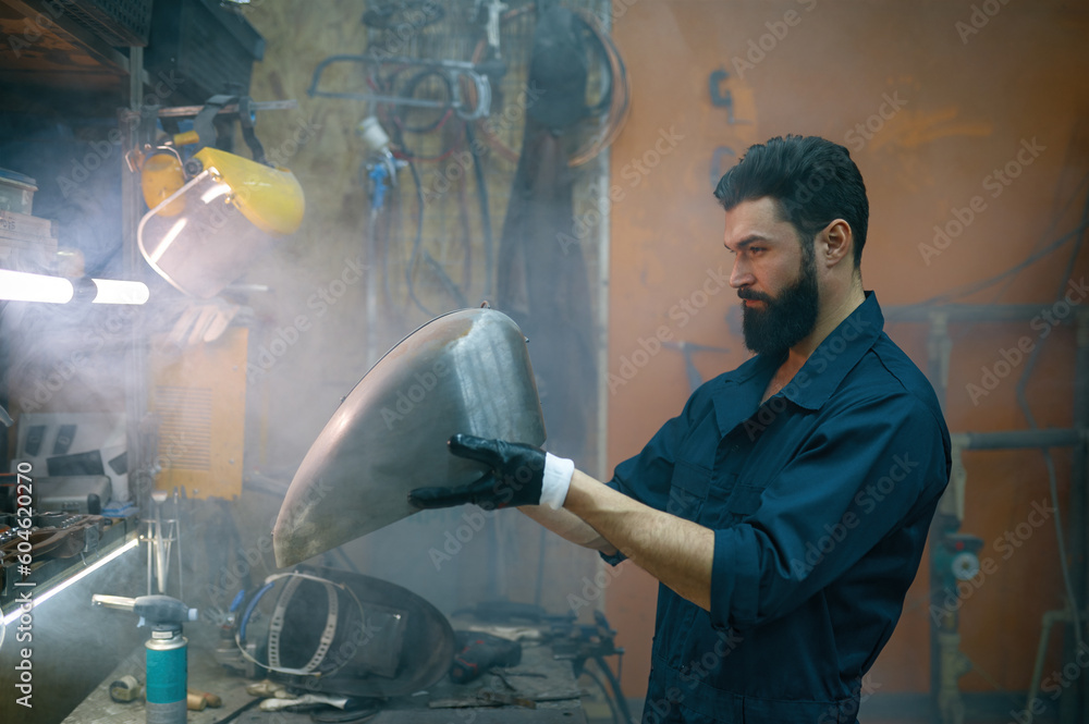 © Nomad_Soul - Serious concentrated repairman inspecting new welded part for motorcycle © Nomad_Soul - Serious concentrated repairman inspecting new welded part for motorcycle