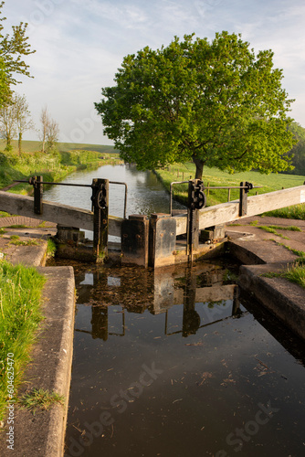 Lock and lock gates at Tyrley Locks on the Shropshire Union Canal in England. Trees reflected in still water on a sunny morning