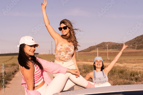 The beautiful three friends enjoy the summer vacation trip and cheerfully raise their hands.