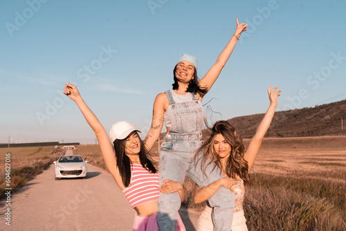Three young European girls having fun outdoors on a road during the summer - Friends enjoying a day on vacation