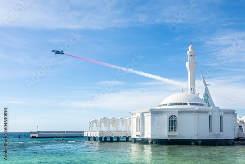 Jet with smoke trace over Alrahmah floating mosque with sea in foreground, Jeddah, Saudi Arabia photo