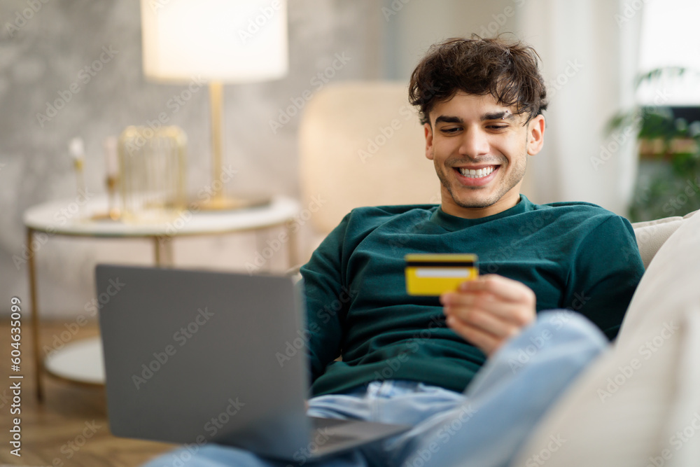 Guy Enjoying Online Shopping Using Laptop And Credit Card Indoors Guy Enjoying Online Shopping Using Laptop And Credit Card Indoors