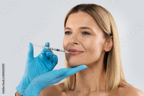 Attractive middle aged lady getting beauty injection in her lips