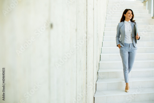 Obraz na płótnie Young business woman walking down the stairs and holding laptop