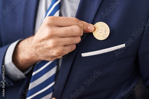 Young hispanic man business worker holding bitcoin at office