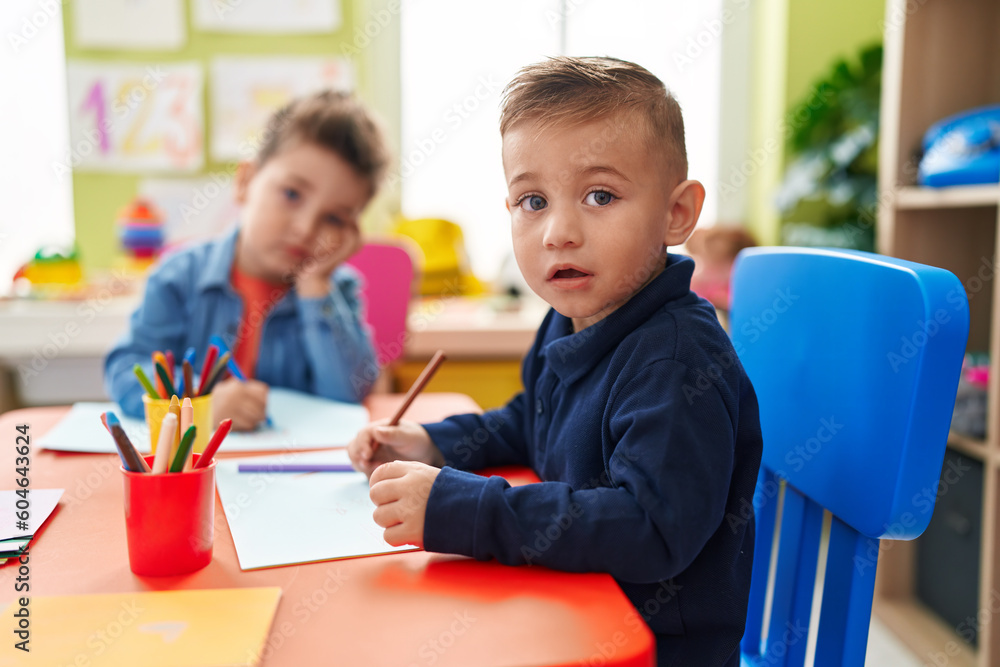 Adorable boys preschool students sitting on table drawing on paper at kindergarten Adorable boys preschool students sitting on table drawing on paper at kindergarten