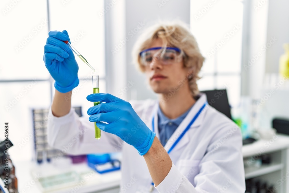 Young blond man scientist pouring liquid on test tube at laboratory Young blond man scientist pouring liquid on test tube at laboratory