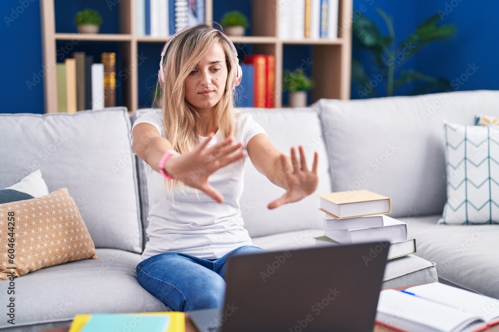 Young blonde woman studying using computer laptop at home doing frame using hands palms and fingers, camera perspective Young blonde woman studying using computer laptop at home doing frame using hands palms and fingers, camera perspective