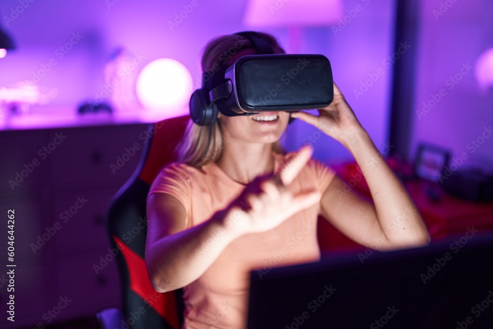 Young blonde woman streamer playing video game using virtual reality glasses at gaming room Young blonde woman streamer playing video game using virtual reality glasses at gaming room