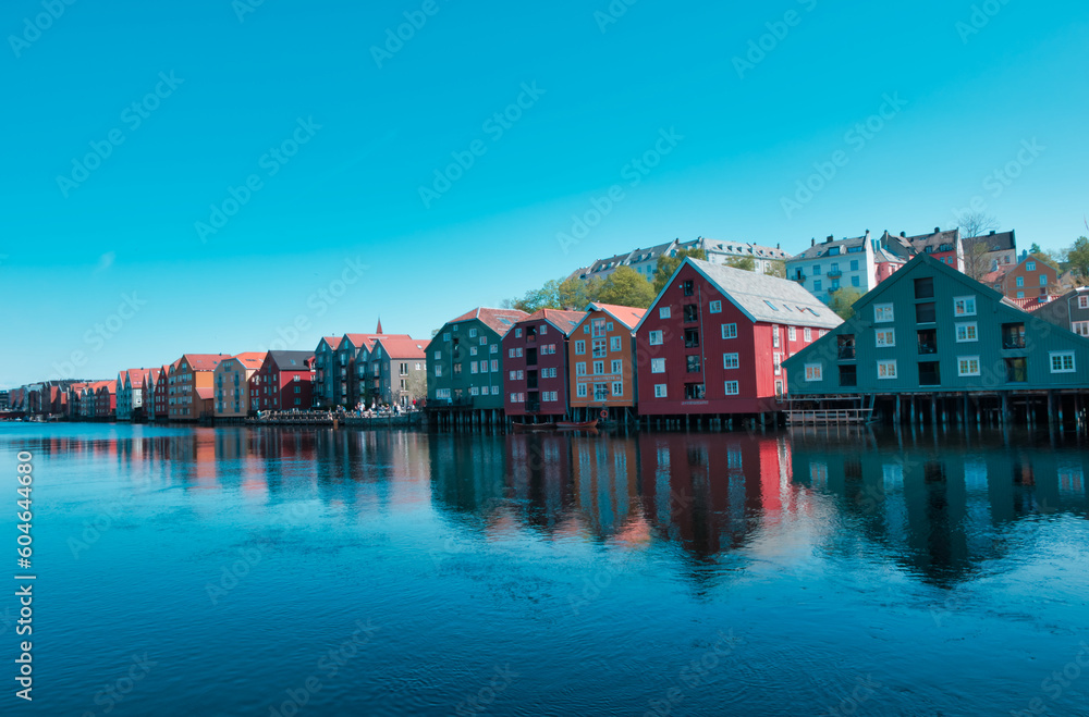 A peaceful spring day in Trondheims Bakklandet district, Norway. Blue sky reflects off the water and white buildings of this charming residential area. A peaceful spring day in Trondheims Bakklandet district, Norway. Blue sky reflects off the water and white buildings of this charming residential area.