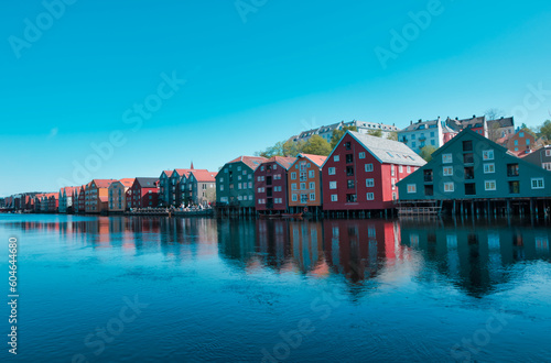 A peaceful spring day in Trondheims Bakklandet district, Norway. Blue sky reflects off the water and white buildings of this charming residential area.