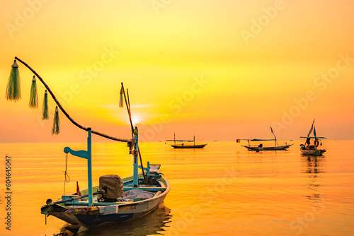Moored boats during sunrise with yellow sky in Kenjeran, Surabaya, Indonesia. photo
