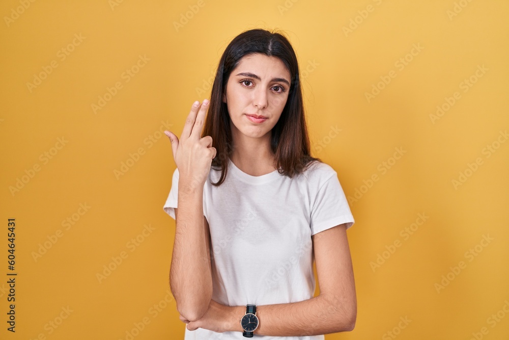 Young beautiful woman standing over yellow background shooting and killing oneself pointing hand and fingers to head like gun, suicide gesture. Young beautiful woman standing over yellow background shooting and killing oneself pointing hand and fingers to head like gun, suicide gesture.