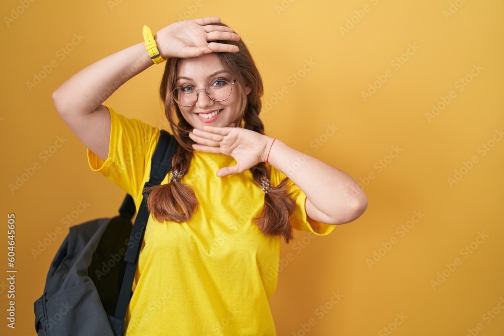 Young caucasian woman wearing student backpack over yellow background smiling cheerful playing peek a boo with hands showing face. surprised and exited Young caucasian woman wearing student backpack over yellow background smiling cheerful playing peek a boo with hands showing face. surprised and exited