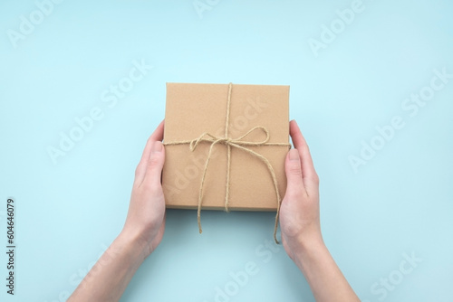 Female hands holding brown ecological package box made of natural corrugated cardboard.