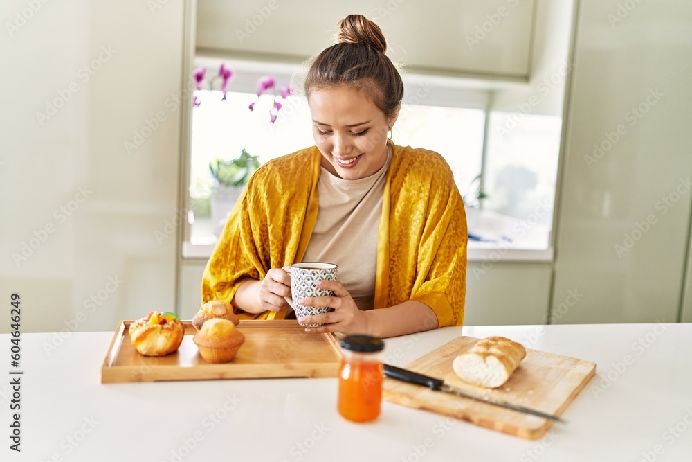 Young beautiful hispanic woman having breakfast drinking coffee at the kitchen Young beautiful hispanic woman having breakfast drinking coffee at the kitchen
